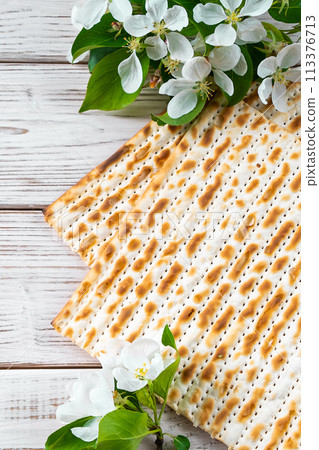 Happy Passover flatlay. Jewish matzo bread and flowers on white wooden background. Happy Passover flatlay. Jewish matzo bread and flowers on white wooden background. 113376713