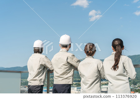 Rear view of male and female staff in the manufacturing, construction, transportation and construction industries wearing work clothes 113376920
