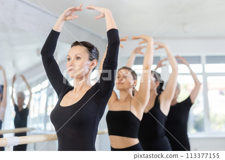Girls in ballet class perform fifth position with participation of mature female mentor 113377155