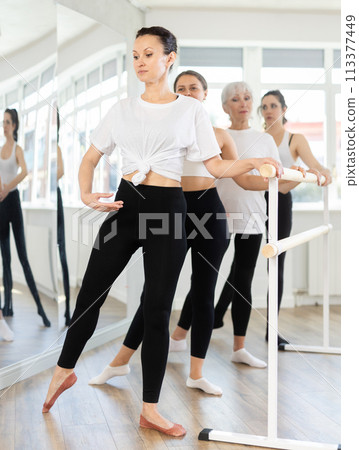 Graceful women of different ages practice at ballet stand in fifth position Graceful women of different ages practice at ballet stand in fifth position 113377449