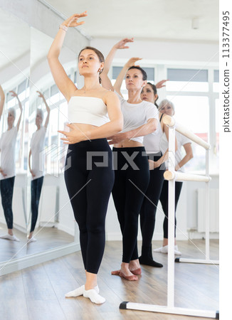 Girls in ballet class perform forth position with participation of mature female mentor 113377495