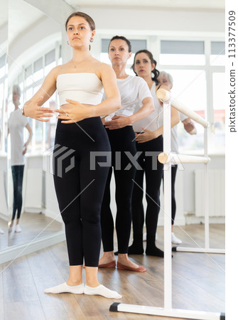 Girls in ballet class perform first position with participation of mature female mentor Girls in ballet class perform first position with participation of mature female mentor 113377509