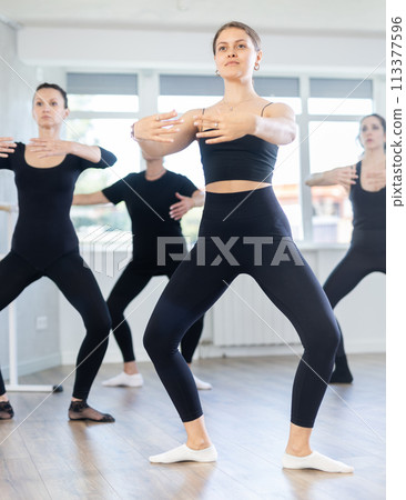 Girls in ballet class perform composition with grand plie with participation of mature female mentor Girls in ballet class perform composition with grand plie with participation of mature female mentor 113377596