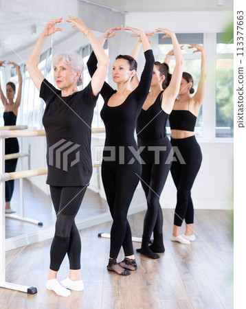 Girls in ballet class perform fifth position with participation of mature female mentor 113377663