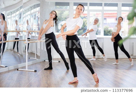 Experienced female ballet dancer rehearsing with group in studio 113377696