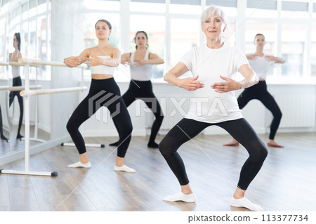 Elderly woman leading ballet class with female dancers Elderly woman leading ballet class with female dancers 113377734