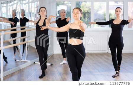 Young woman in group lesson with students rehearses, practices ballet dance, staging. 113377776
