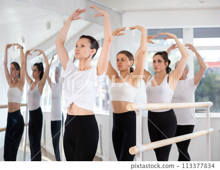 Woman maintaining fifth position during group ballet workout 113377834