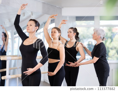 Group of ballet dancers learn new moves under the guidance of an experienced choreographer Group of ballet dancers learn new moves under the guidance of an experienced choreographer 113377882