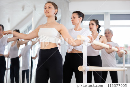 Girls in ballet class perform second position with participation of mature female mentor 113377905
