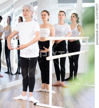 Group of women stand in position at ballet barre 113378037