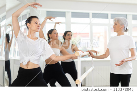 Group of dancers standing in grand plie ballet position in fitness room Group of dancers standing in grand plie ballet position in fitness room 113378043