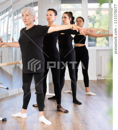 Elderly woman mastering second position at ballet barre Elderly woman mastering second position at ballet barre 113378077