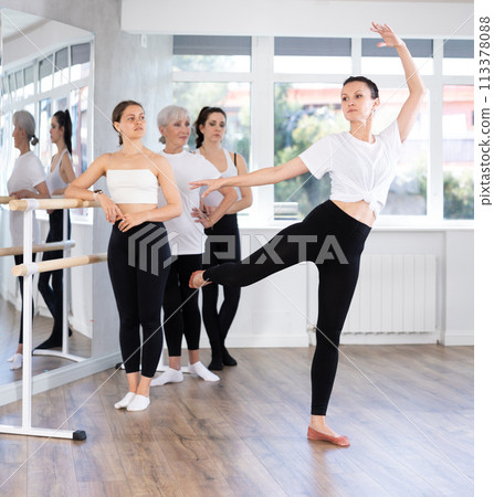 Woman teacher demonstraiting ballet moves in front of women of different ages during group ballet training Woman teacher demonstraiting ballet moves in front of women of different ages during group ballet training 113378088