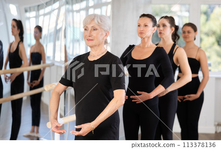 Group of women stand in position at ballet barre Group of women stand in position at ballet barre 113378136