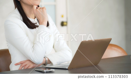 Middle-aged woman thinking while looking at a laptop Middle-aged woman thinking while looking at a laptop 113378303