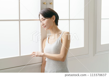 一名30多歲的女子靠在窗戶上 一名30多歲的女子靠在窗戶上 113378637