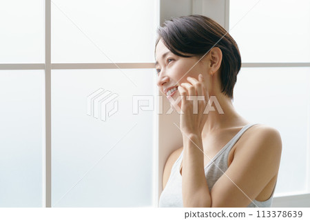 A woman in her 30s leaning against a window 113378639