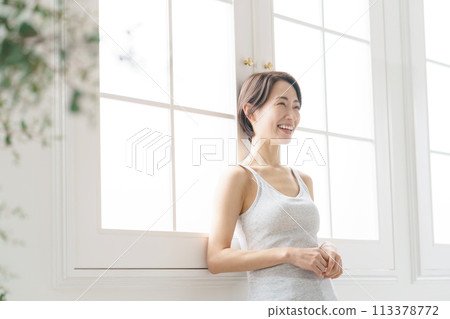 A woman in her 30s standing by the window 113378772