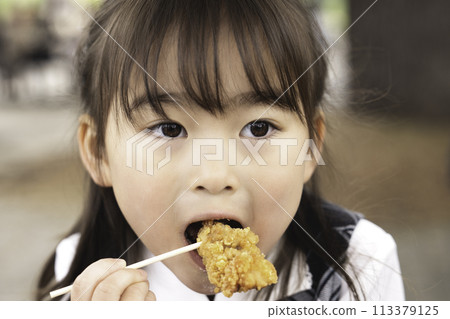 Girl eating fried chicken on a picnic Girl eating fried chicken on a picnic 113379125