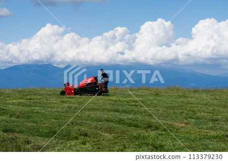 夏季高原草甸紅色拖拉機割草機初夏積雨雲 113379230