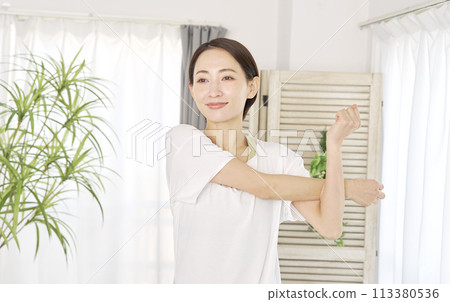 一名 40 多歲的婦女在家中伸展雙臂 113380536