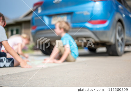 Children sitting on a driveway behind a vehicle in a blind spot out of view of the driver.  113380899