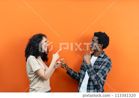 Young Couple Pointing Each Other On Vibrant Orange Young Couple Pointing Each Other On Vibrant Orange 113381320