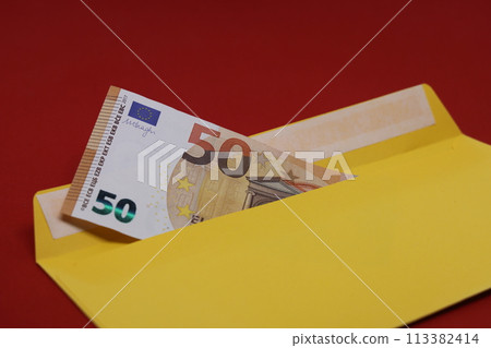 Banknotes in a yellow envelope on a red background. Bribery concept. Salary in envelopes, fraud. Banknotes in a yellow envelope on a red background. Bribery concept. Salary in envelopes, fraud. 113382414