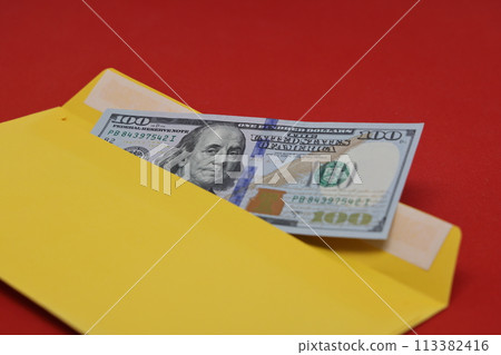 Banknotes in a yellow envelope on a red background. Bribery concept. Salary in envelopes, fraud.cept. Salary in envelopes. Financial fraud. 113382416