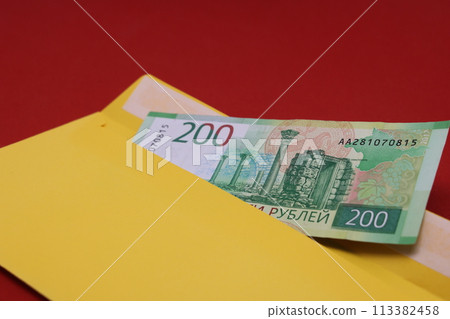 Banknotes in a yellow envelope on a red background. Bribery concept. Salary in envelopes, fraud. Banknotes in a yellow envelope on a red background. Bribery concept. Salary in envelopes, fraud. 113382458