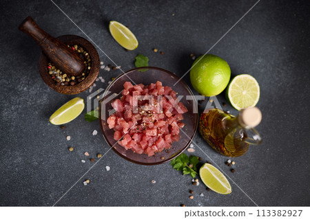 Sliced and chopped tuna fillet in glass bowl at domestic kitchen cooking traditional tartare 113382927