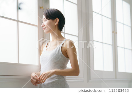 一個穿著背心的女人看著窗外 一個穿著背心的女人看著窗外 113383433