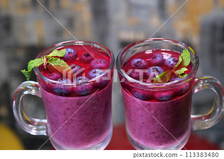 taking out a teaspoon from a glass cup delicious blueberry dessert with mint and cream jelly cooking close-up food human hand on a dark background taking out a teaspoon from a glass cup delicious blueberry dessert with mint and cream jelly cooking close-up food human hand on a dark background 113383480