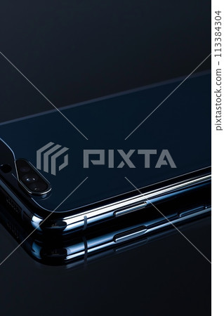 A smartphone with a thin navy body on a black background. Close-up A smartphone with a thin navy body on a black background. Close-up 113384304