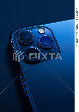 A close-up on a smartphone's camera array, set against a deep navy background 113384409