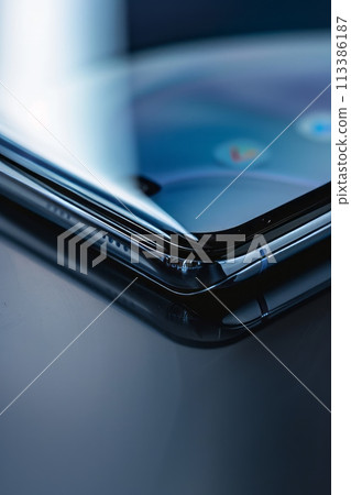 Close-up of a smartphone's edge showing part of the display and buttons, with a reflection 113386187