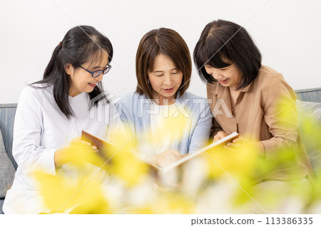 Three women watching the album Three women watching the album 113386335