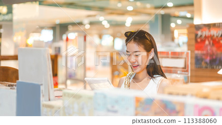 Portrait of beautiful young woman university student choosing book at bookstore shop 113388060