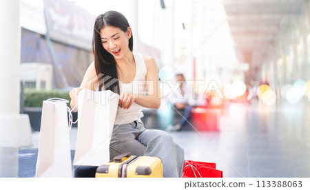 Asian woman long hair wearing white tanktop looking in shopping bag Asian woman long hair wearing white tanktop looking in shopping bag 113388063