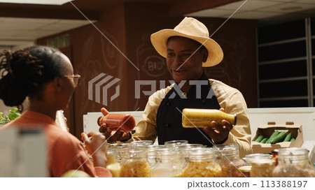 Merchant presenting additives free homemade sauces for tasty meals, recommending ethically sourced pantry supplies and pasta. Seller promoting his organic bulk products in glass jars. Camera 1. Merchant presenting additives free homemade sauces for tasty meals, recommending ethically sourced pantry supplies and pasta. Seller promoting his organic bulk products in glass jars. Camera 1. 113388197