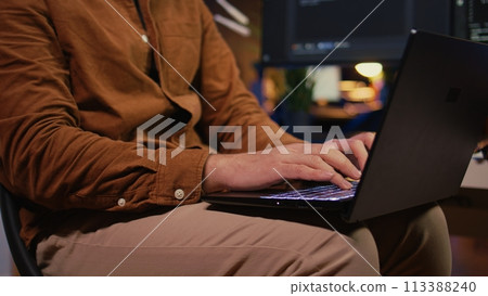 Remote programmer starting job shift in personal office at home, taking laptop out of bag. Teleworker unpacking backpack, writing lines of code on notebook keyboard, camera B close up 113388240