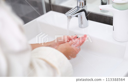 Woman washing her hands under water from tap in bathroom closeup Woman washing her hands under water from tap in bathroom closeup 113388564