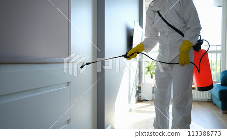 Worker in protective overalls and gloves disinfecting apartment Worker in protective overalls and gloves disinfecting apartment 113388773