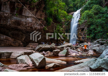Serene Waterfall Oasis Amidst Rugged Rocks and Greenery 113389105