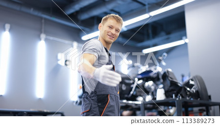 Smiling young car mechanic stands in workshop closeup Smiling young car mechanic stands in workshop closeup 113389273