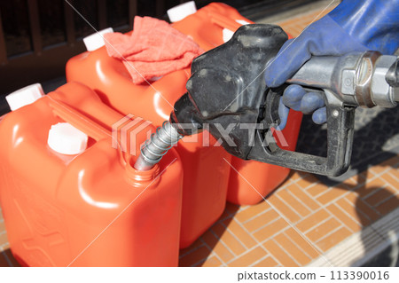 Filling a red plastic tank with kerosene Filling a red plastic tank with kerosene 113390016
