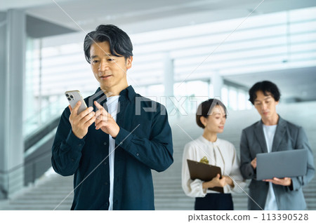 Middle-aged businessman operating a smartphone in the office 113390528