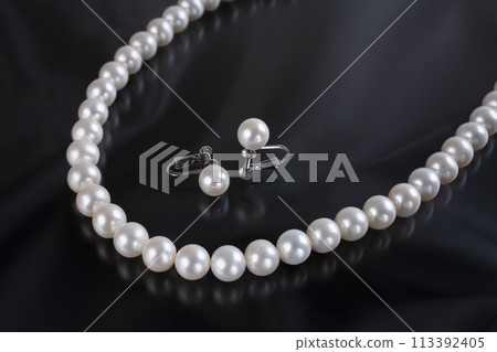 Pearl necklace and earrings on a black background Pearl necklace and earrings on a black background 113392405
