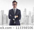 Businessman in a suit confidently posing with arms crossed in a modern office setting 113398506